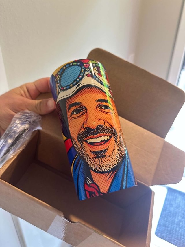 A personalized tumbler with a colorful pop-art portrait, held over its open shipping box just after unboxing